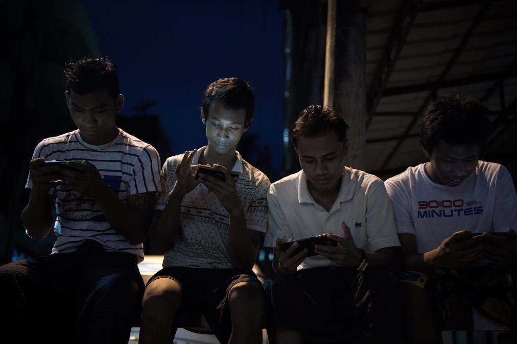 Young men browse Facebook on their smartphones in Yangon. Photo: AFP