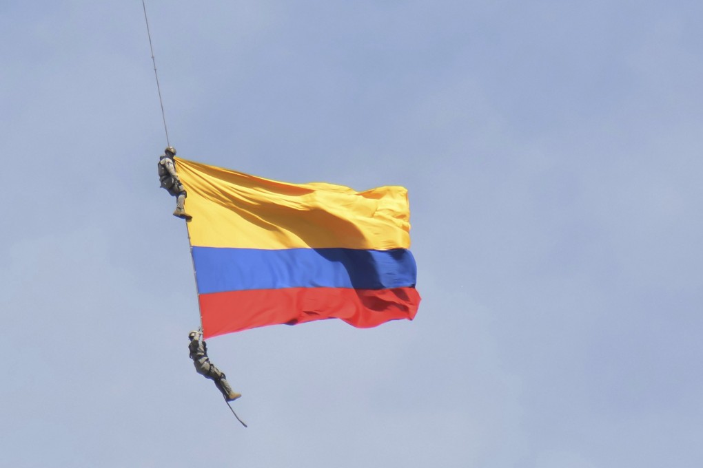The two members of Colombia’s air force hang from a cable under a helicopter before the accident. Photo: AP