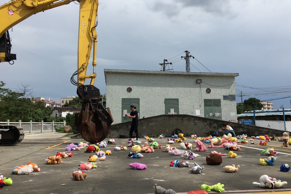 A large excavator with a metal claw picks up hundreds of dolls donated by Baishizhou villagers and flings them over the Shenzhen city border on August 4, 2019. This protest art, called “Shenzhen Dolls”, earned artist Wang Renzheng, known as Nut Brother, a visit from police this week.
