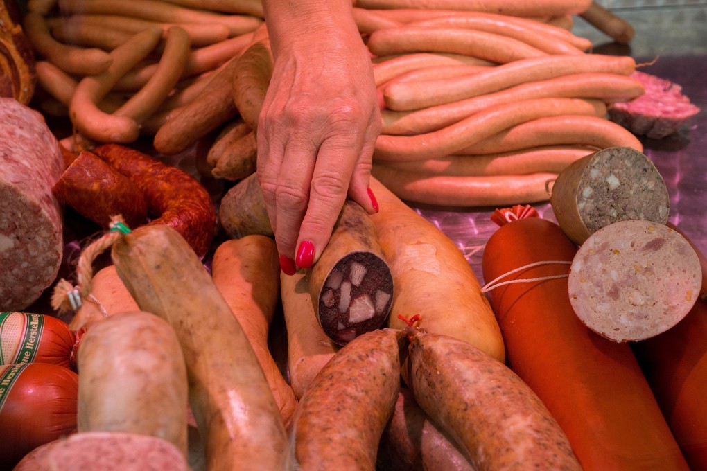 A butcher selects a red meat sausage from a market stall in Berlin, Germany. Photo: Bloomberg