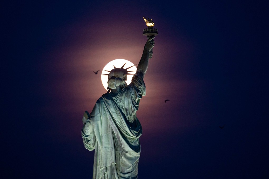 A full moon rises behind the Statue of Liberty in New York City. Photo: AFP
