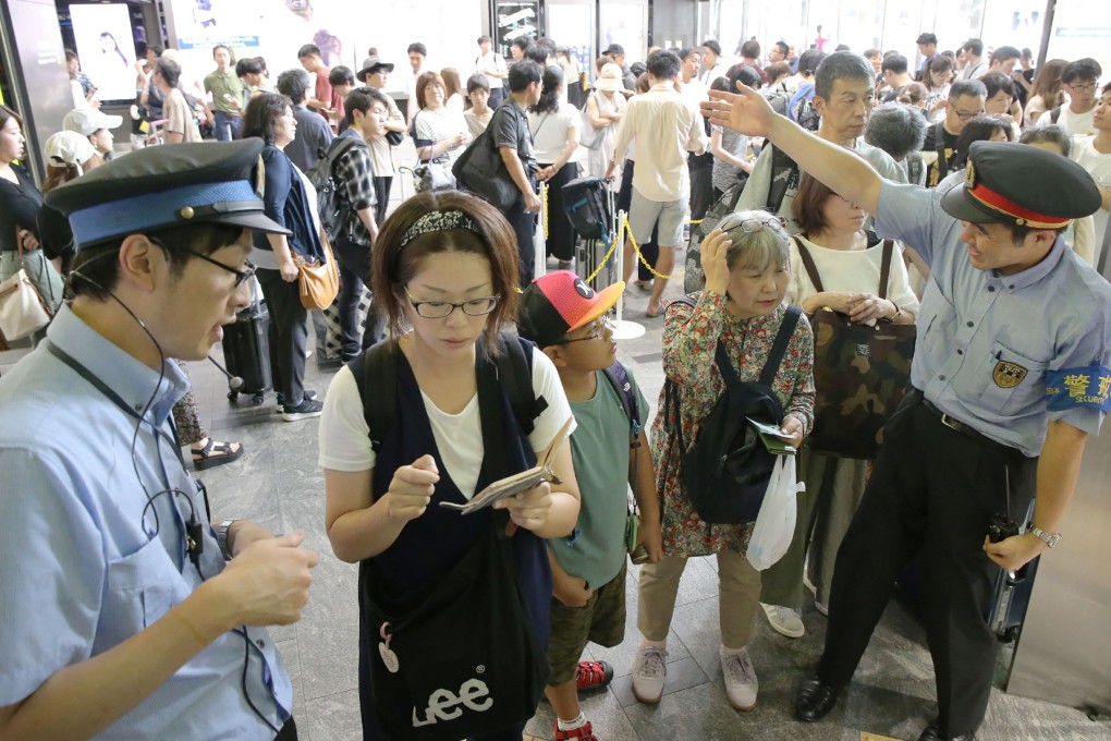 Railway employees assist stranded passengers at the Hakata Shinkansen station in the city of Fukuoka. Photo: AFP