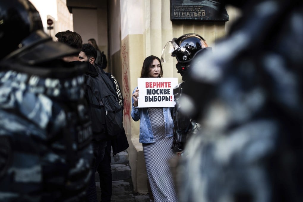 A woman holds a poster reading “Give us back our elections in Moscow!" in front of police during a protest in Moscow on August 10. Photo: AP