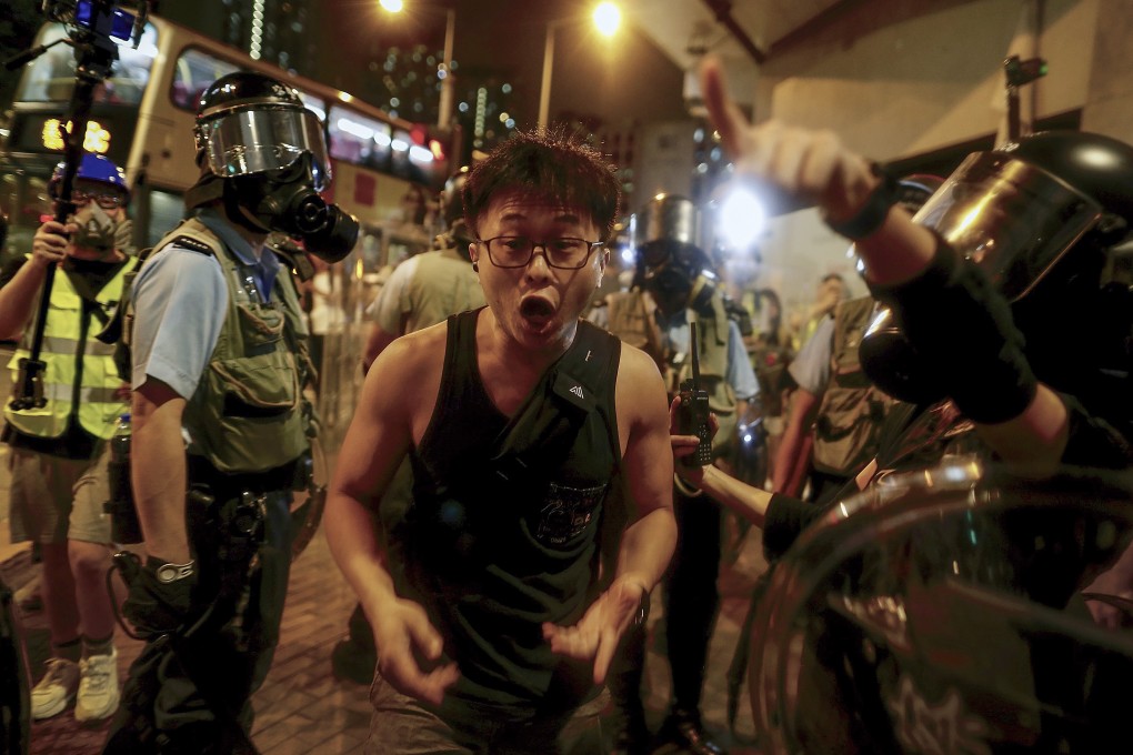 Riot police order a local man to move out of the way during protests on the night of August 14. Photo: AP