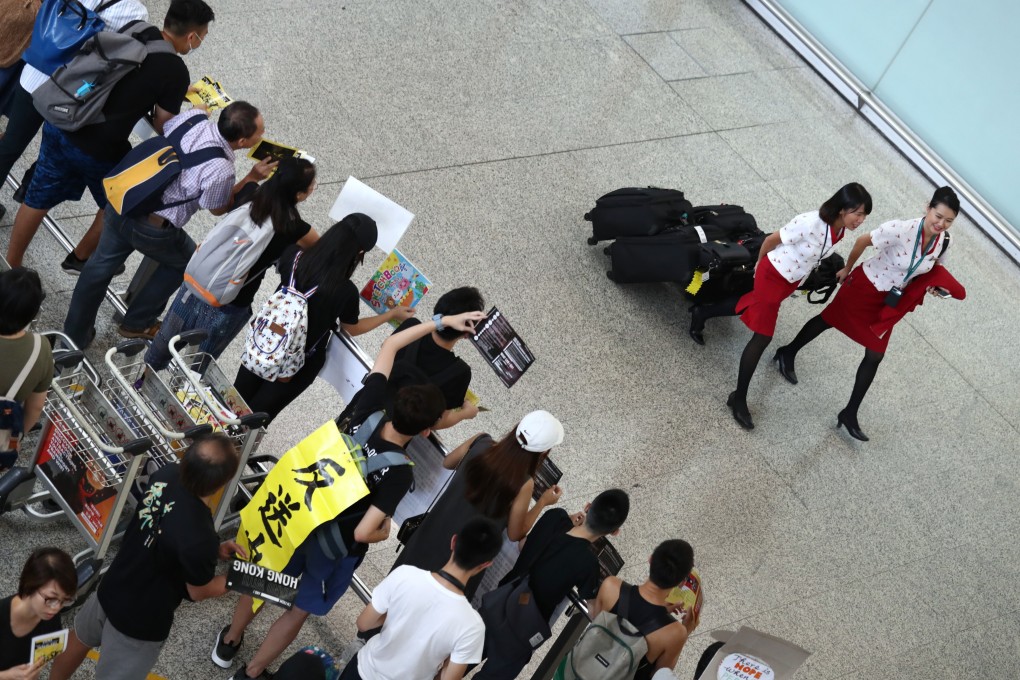 Cathay Pacific cabin crew walk past anti-government protesters during the sit-in at Hong Kong International Airport. Photo: Nora Tam