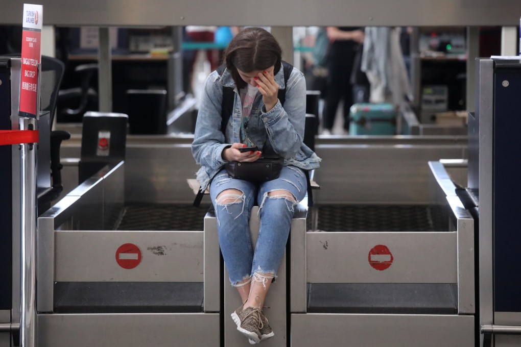 A traveller stranded at the Hong Kong International Airport on August 14 looks at her phone. Protest action at the airport on two consecutive days caused hundreds of flight cancellations. Photo: K. Y. Cheng