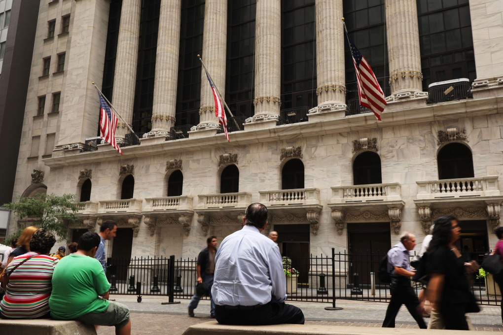 People sit outside the New York Stock Exchange on Wednesday. Concerns over a recession in America sent stocks plummeting in all three major US indices that day, with the Dow dropping more than 700 points. Photo: AFP