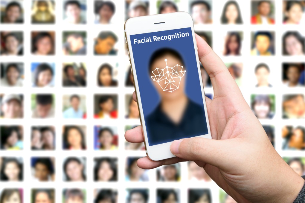 Man hand holding smart phone with blue screen and blur human faces background. Photo: Shutterstock