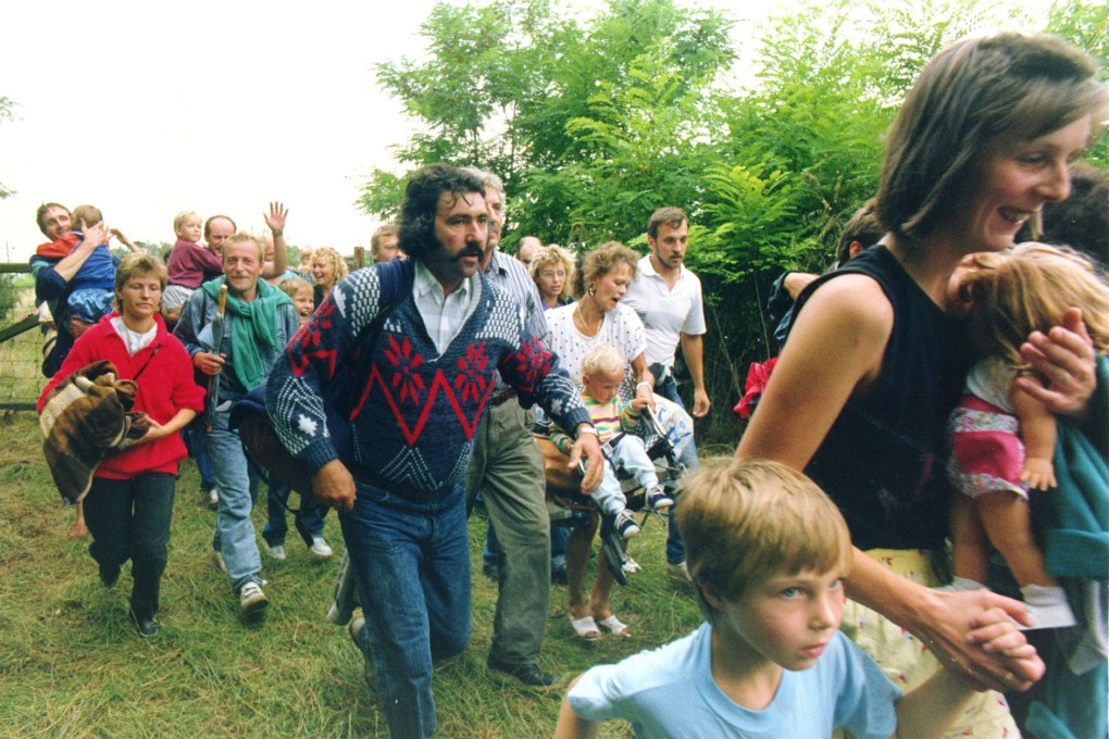 East Germans surprise Hungarian border guards and rush through a gate into Moerbisch, Austria in 1989. File photo: AP