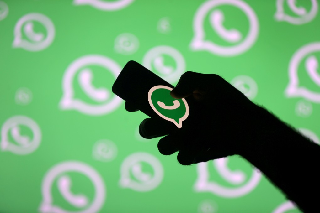 A man poses with a smartphone in front of a displayed Whatsapp logo in this illustration. Photo: Reuters