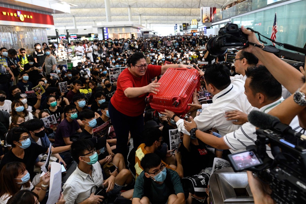 A tourist hands her luggage to security guards as she tries to enter the departure gate at Hong Kong airport during a demonstration on August 13. Photo: AFP