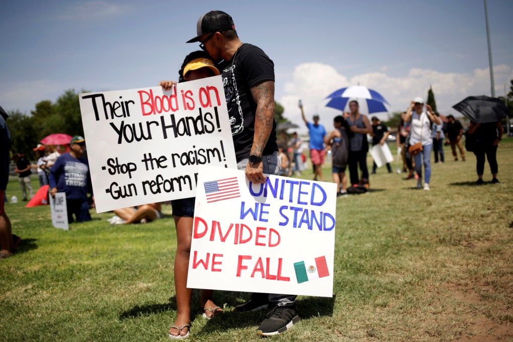 Protesters embrace while holding placards against the visit of US President Donald Trump after the shooting at a Walmart store in El Paso, Texas. Photo: Reuters