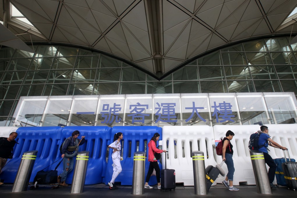Passengers walk past water-filled barriers at Hong Kong International Airport. The barriers were put in place to prevent anti-government protestors from occupying the airport after they have paralysed operations last week. Photo: David Wong