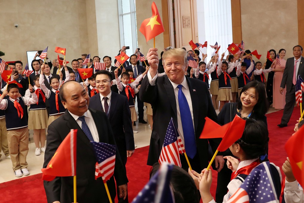 US President Donald Trump waves a Vietnamese flag as he is greeted by students during a meeting with Vietnamese Prime Minister Nguyen Xuan Phuc in Hanoi in February.