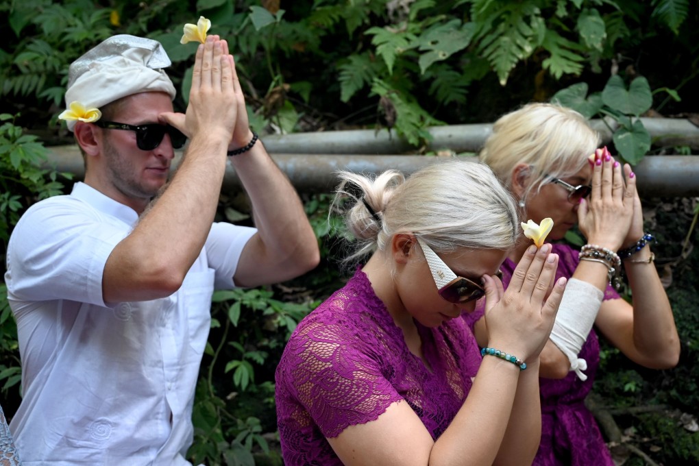 Czech couple Sabina Dolezalova (centre) and Zdenek Slouka (left) pray ahead of a purification ritual at the Beji Temple, on Indonesia's resort island of Bali on August 15, after a disrespectful video they posted online went viral. Photo: AFP