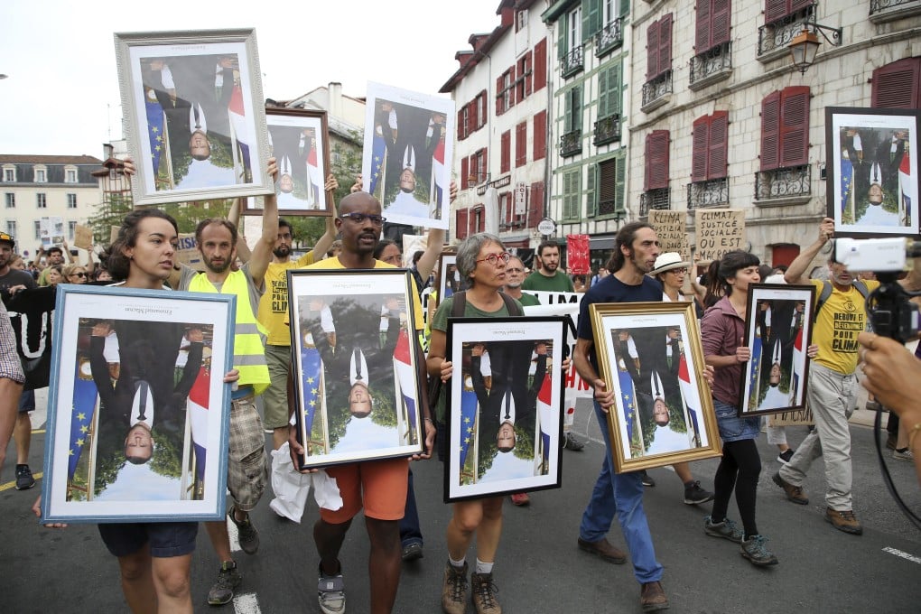 Demonstrator hold upside down portraits of French President Emmanuel Macron during a protest through the streets of Bayonne, France. Photo: AP Photo