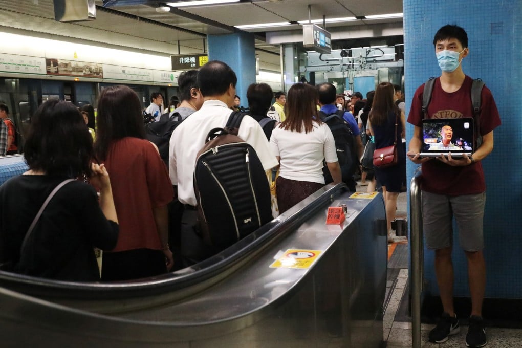 A protester plays a video of alleged police brutality as passengers arrive on the platform at Kowloon Tong MTR station, on August 21. The protesters’ five demands of the government include the setting up of an independent inquiry into police action against demonstrators. Photo: Reuters