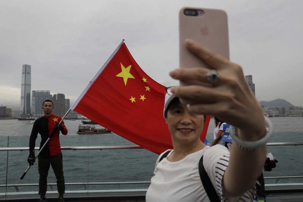 A woman takes a selfie in front of a man holding the Chinese flag during a rally in Hong Kong on August 17. Twitter says it has suspended more than 200,000 accounts it believes were part of a Chinese government campaign targeting the protests in Hong Kong. Photo: AP
