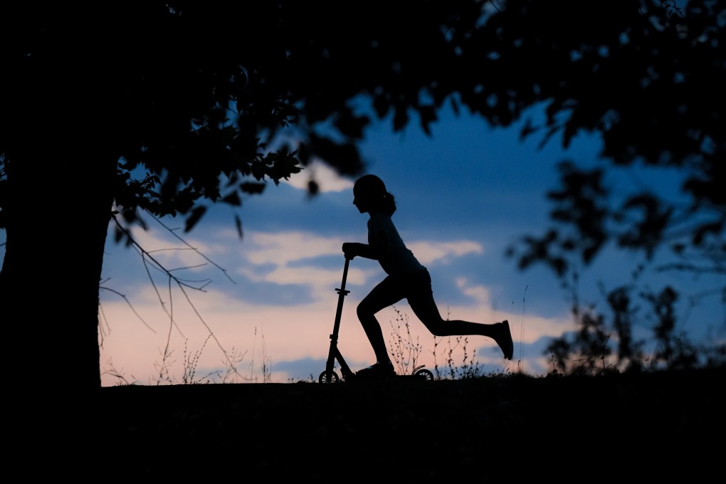 A child rides a scooter at dusk in a park in Bucharest, Romania. Photo: AP