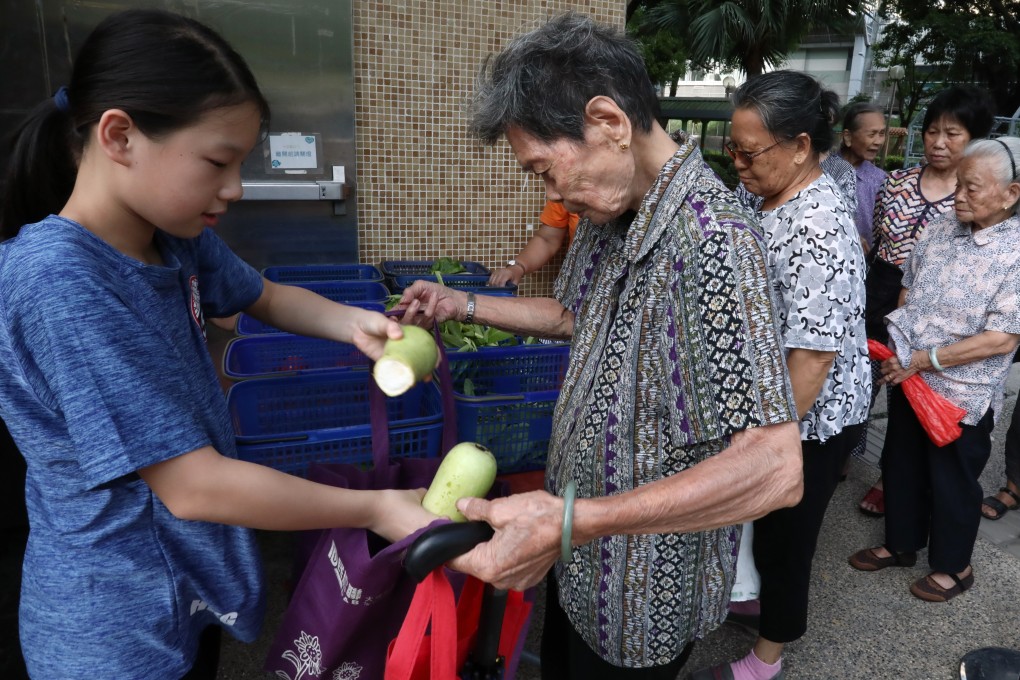 Primary school student and food Grace volunteer Maggie Pok (left), distributes vegetables to the elderly in Tai Po as part of the food recycling scheme. Photo: Jonathan Wong