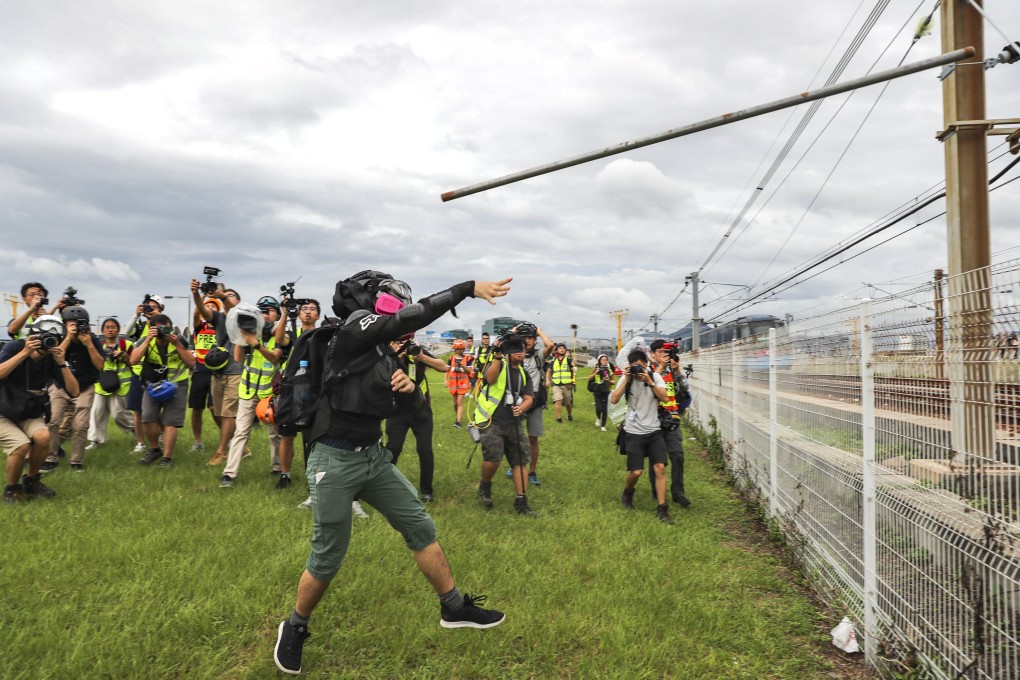A protester launches a pole onto the tracks of the Airport Express. Photo: Sam Tsang