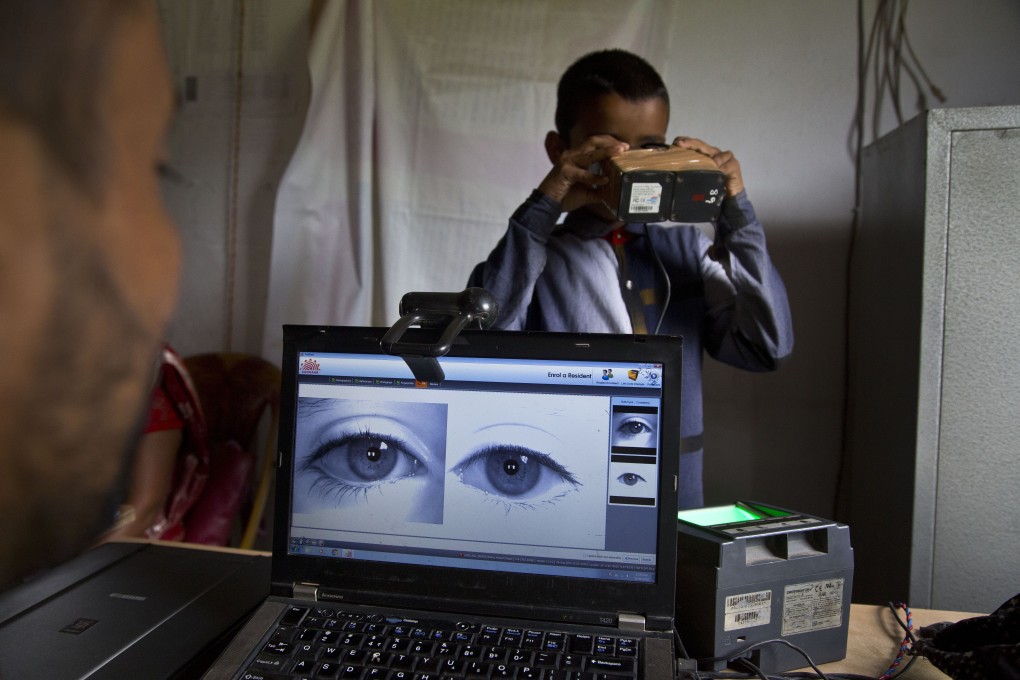 A National Register of Citizens officer takes a photograph of the eyes of a boy at an NRC centre in Gauhati. Photo: AP