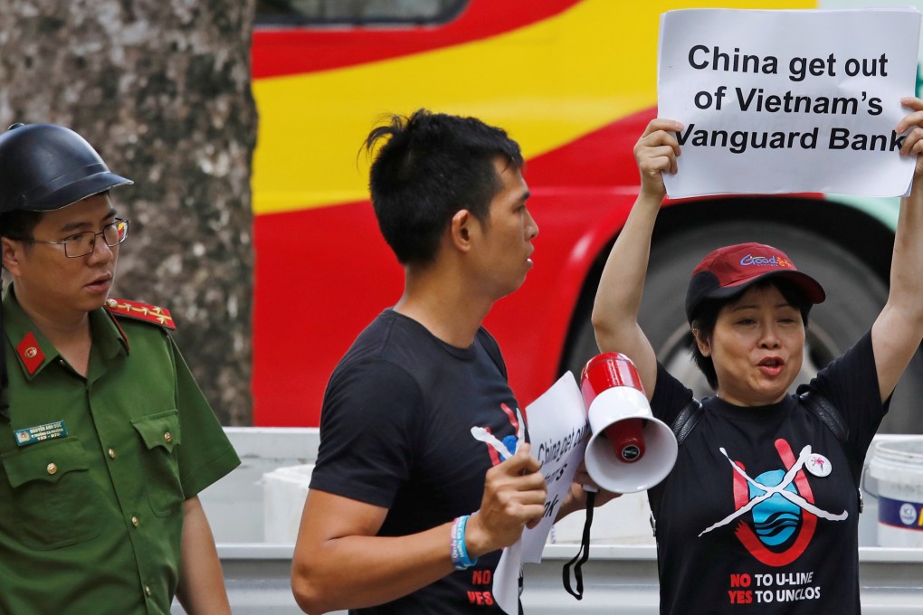 A Vietnamese policeman (left) approaches anti-China protesters in front of the Chinese embassy in Hanoi on August 6. Photo: Reuters