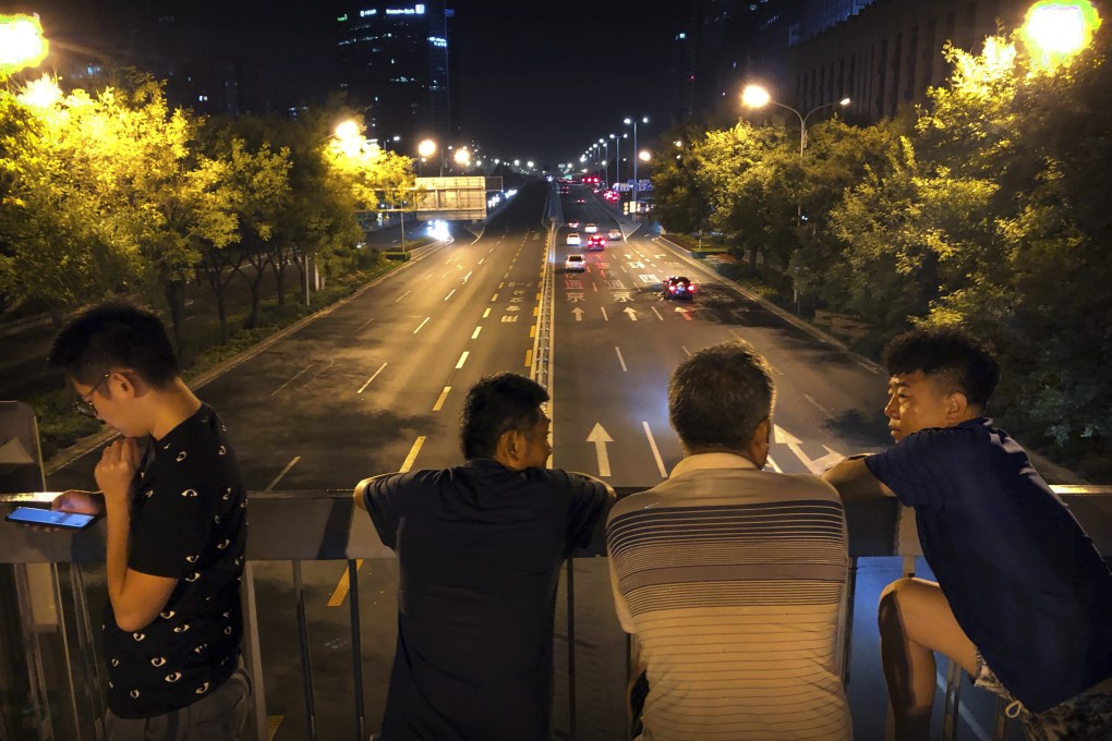 Onlookers gather on a pedestrian bridge to catch a glimpse of preparations for a military parade in Beijing on Saturday. Many of the streets in the central part of China's capital were shut down overnight on Saturday for a rehearsal for what is expected to be a large military parade on October 1 to commemorate the 70th anniversary of Communist China. Photo: AP