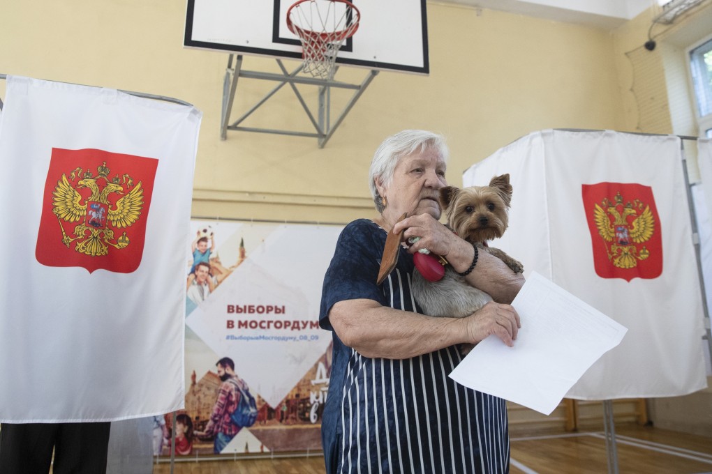 A woman holds her dog and a ballot at a polling station in Moscow on Sunday. Photo: AP