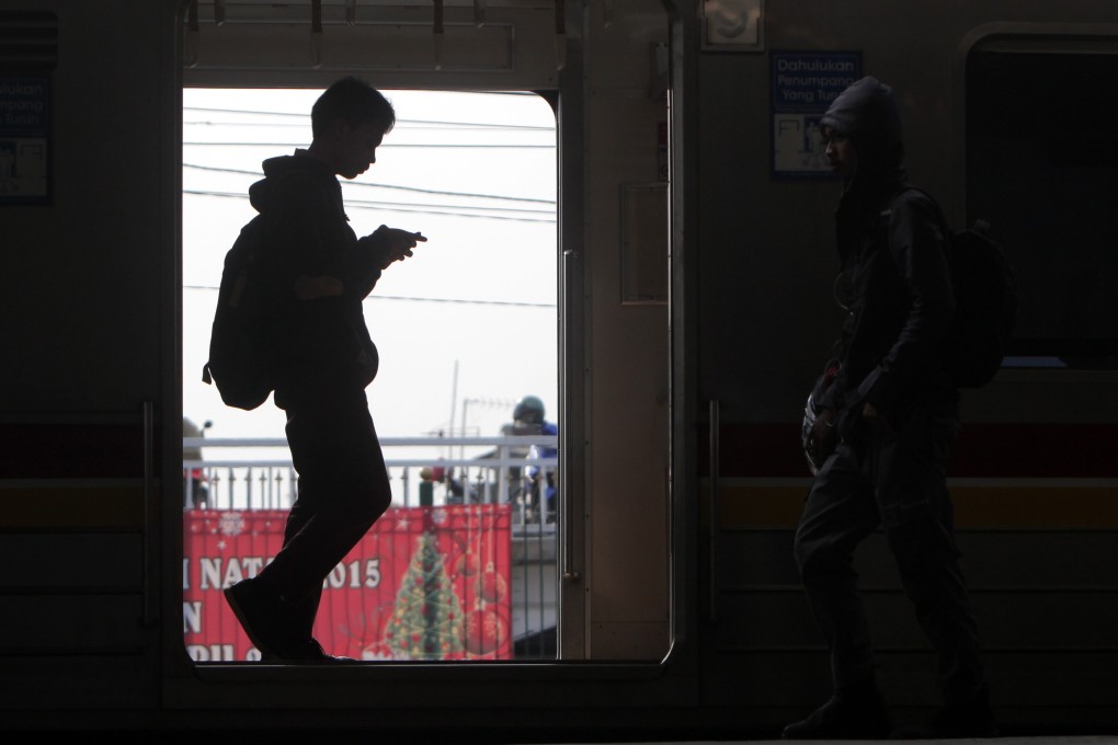 A commuter looking at his mobile phone in Jakarta, Indonesia. Photo: EPA