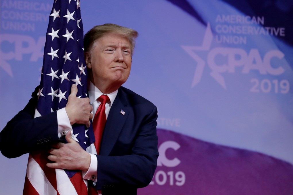 US President Donald Trump hugs the American flag at the Conservative Political Action Conference annual meeting near Washington on March 2. Photo: Reuters