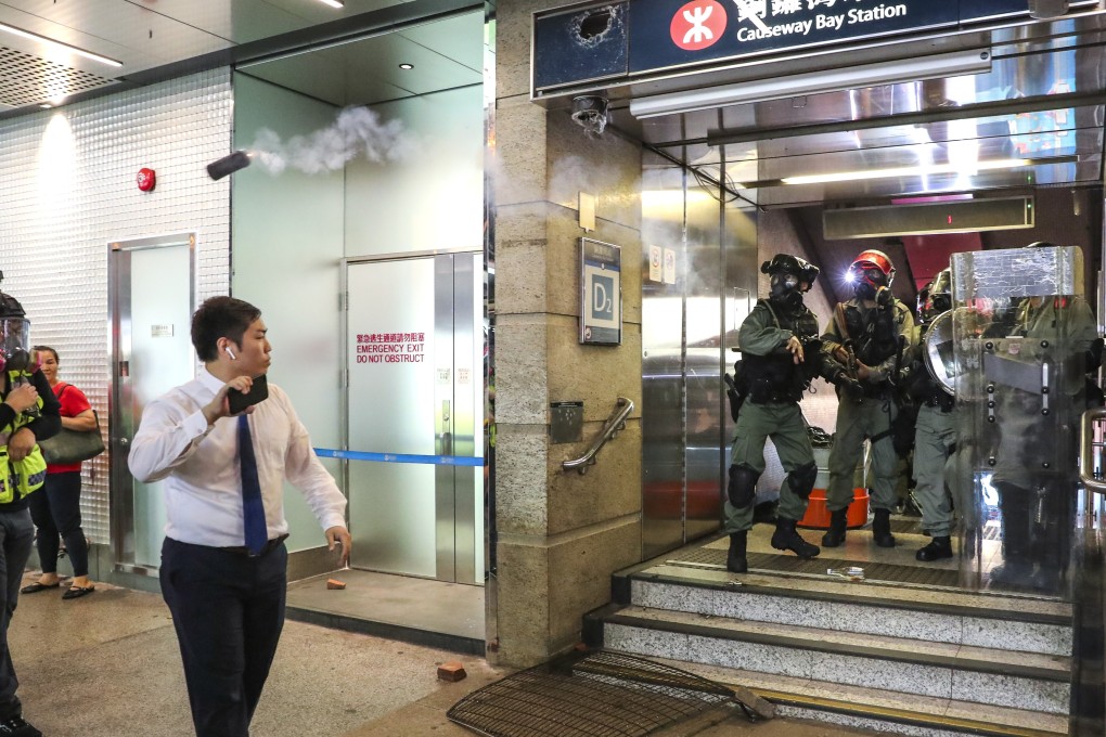 A riot police officer throws a canister of tear gas at journalists without warning outside Causeway Bay station on Sunday. Photo: Sam Tsang