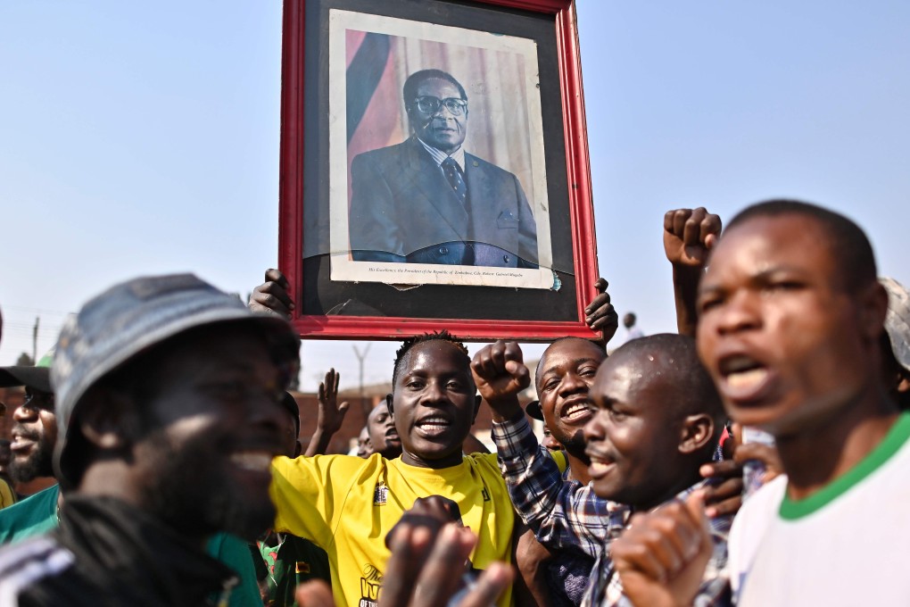 Mourners carrying a portrait of Zimbabwe's late former president Robert Mugabe sing as they wait at the historic Rufaro stadium in the capital, Harare, for the arrival of his body on Thursday. Photo: AFP