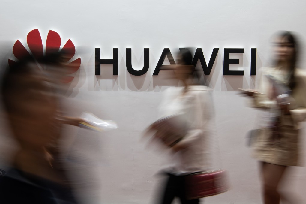 People walk past a Huawei logo during the Consumer Electronics Expo in Beijing. Photo: AFP