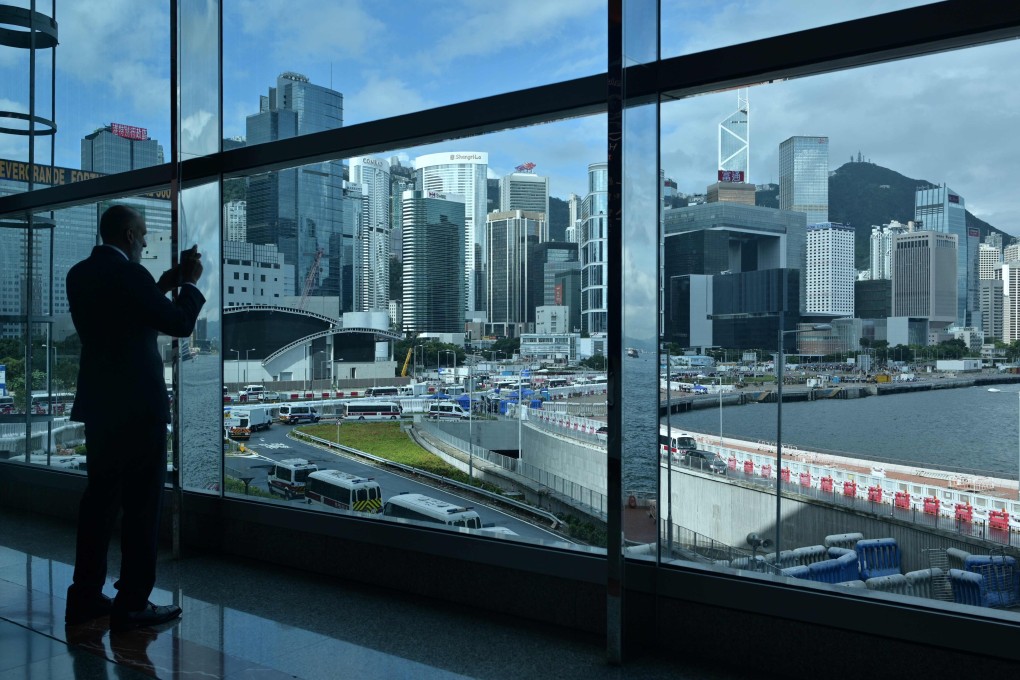 A guest takes a photo of the Hong Kong skyline and protesters gathered near the waterfront after the annual flag raising ceremony to mark the 22nd anniversary of the city's handover from Britain to China on July 1. Photo: AFP