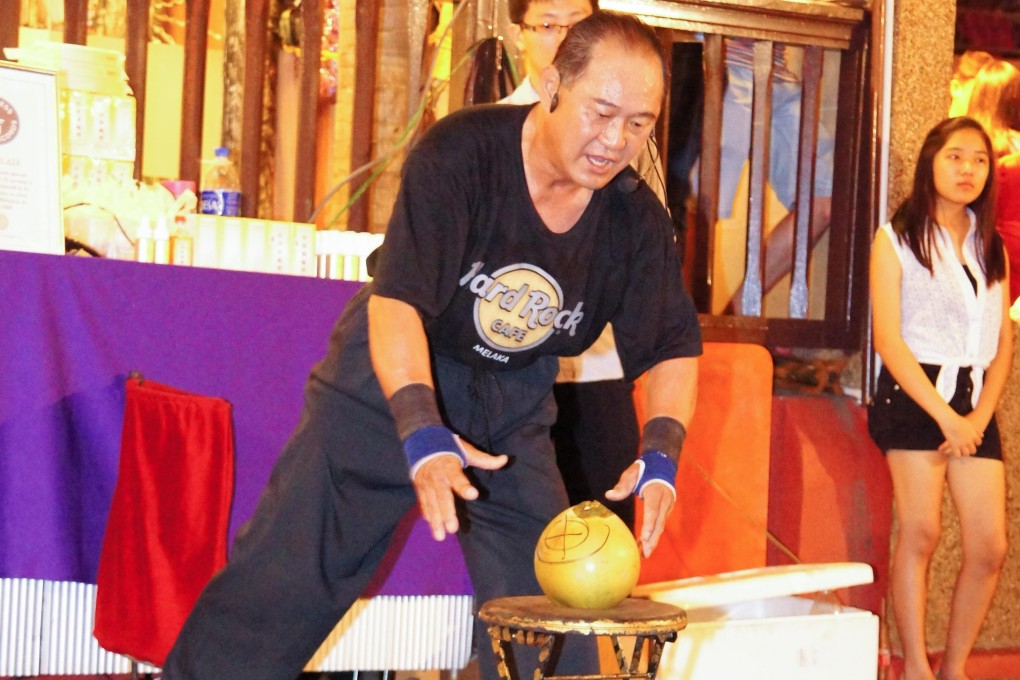 Martial arts master Ho Eng Hui, from Johor in Malaysia, created a world record when he managed to pierce the husks of four coconuts with his index finger in 12.15 seconds. Photo: Alamy