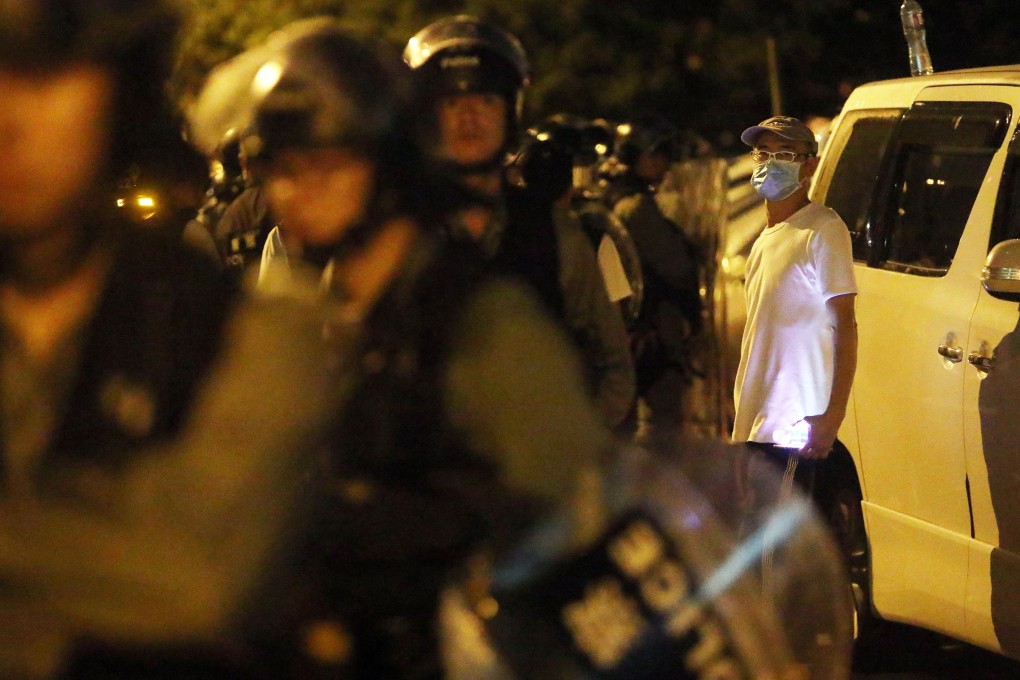 A white-shirted man stands behind riot police in Yuen Long on the night of July 21. Police have been accused of neglected their duties by being slow in responding to that night’s attack on protesters and commuters by armed men. Photo: Winson Wong