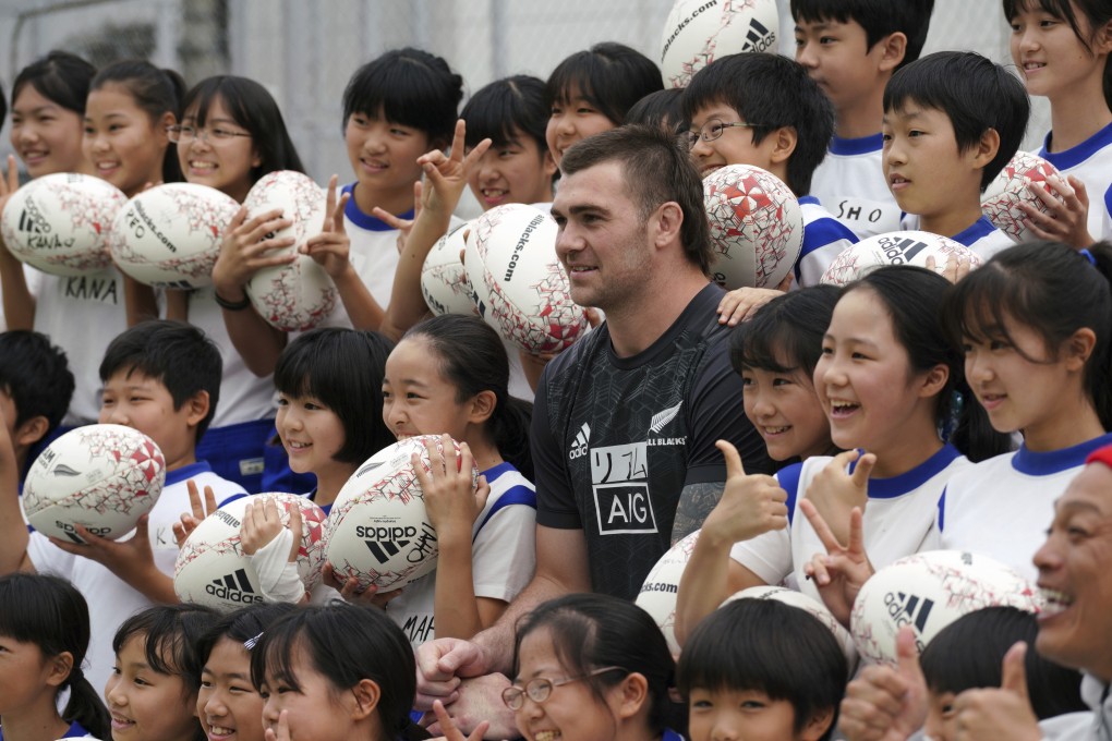 New Zealand’s Liam Squire with Japanese schoolchildren during a rugby clinic in Tokyo. Photo: AP