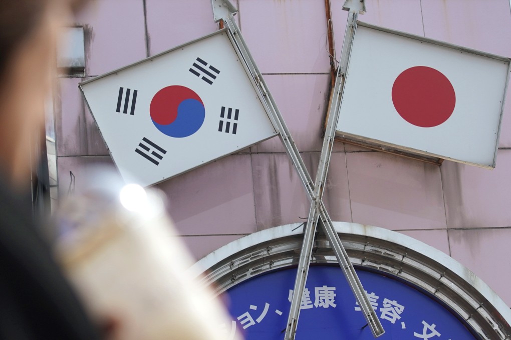 A woman walks past an advertisement featuring Japanese and South Korean flags at a shop in Tokyo. Photo: AP