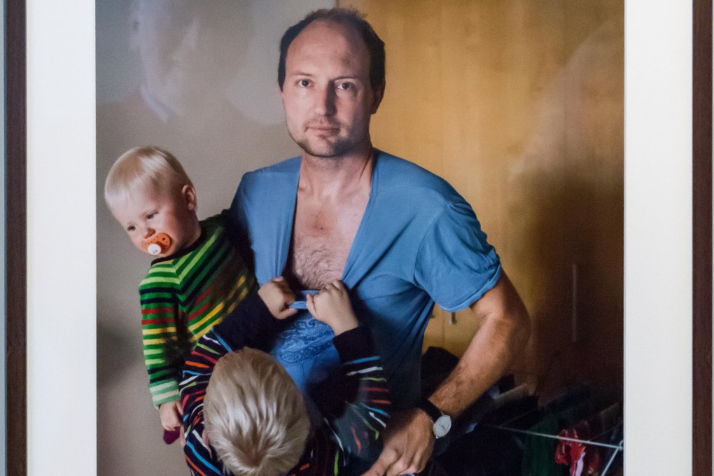 Hanging on to Dad by Johan Bävman, part of his exhibition celebrating Swedish fathers caring for their babies and toddlers on paternity leave. Photo: Tommy Lindholm/Pacific Press/Alamy