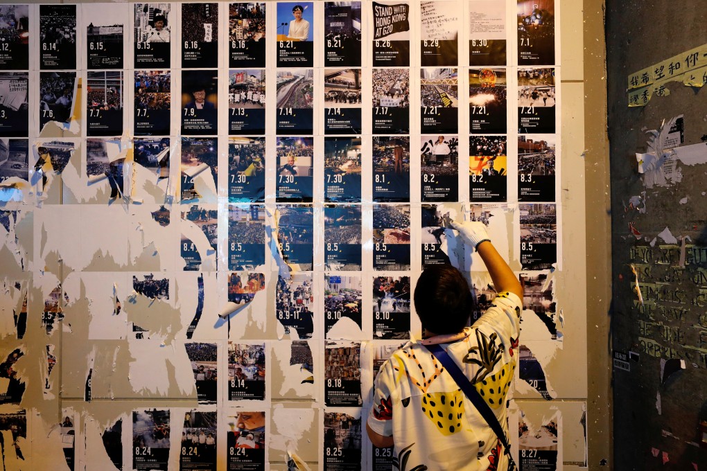 A pro-Beijing supporter removes protest material from a Lennon Wall in a clean-up operation that passed off without major incident on Saturday morning. Photo: Reuters