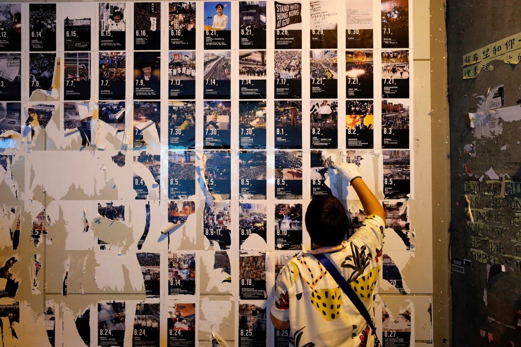 A pro-Beijing supporter removes protest material from a Lennon Wall in a clean-up operation that passed off without major incident on Saturday morning. Photo: Reuters