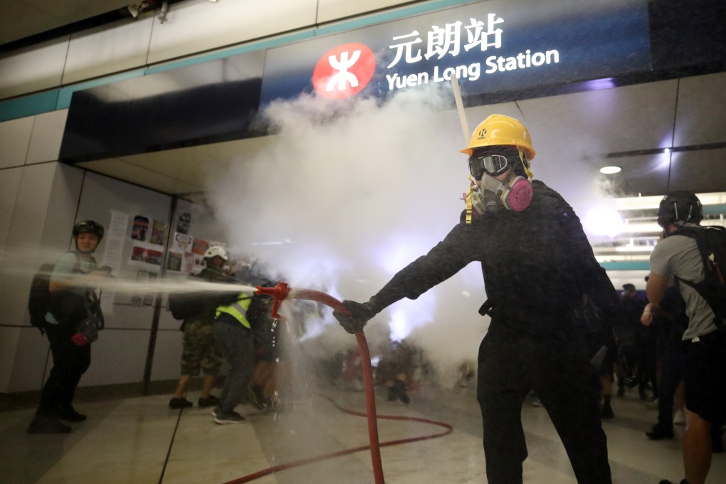 A protester uses a fire hose as Yuen Long MTR station is vandalised. Photo: Winson Wong
