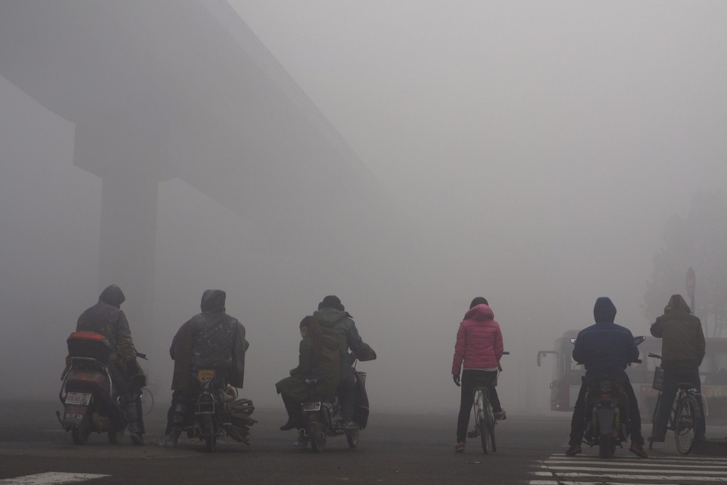 Cyclists and motorcyclists wait for the traffic in heavy smog in Shijiazhuang, Hebei province. Photo: Reuters