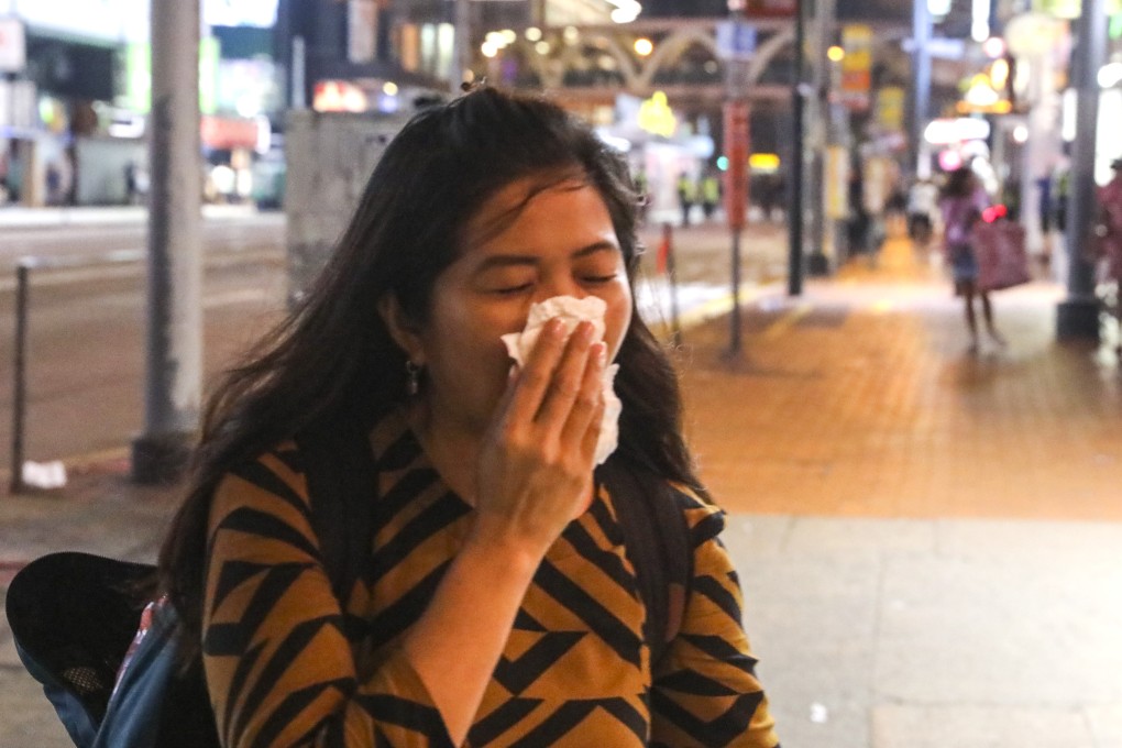 A woman reacts to tear gas in Causeway Bay where railings have been removed by anti-government protesters. Photo: K. Y. Cheng