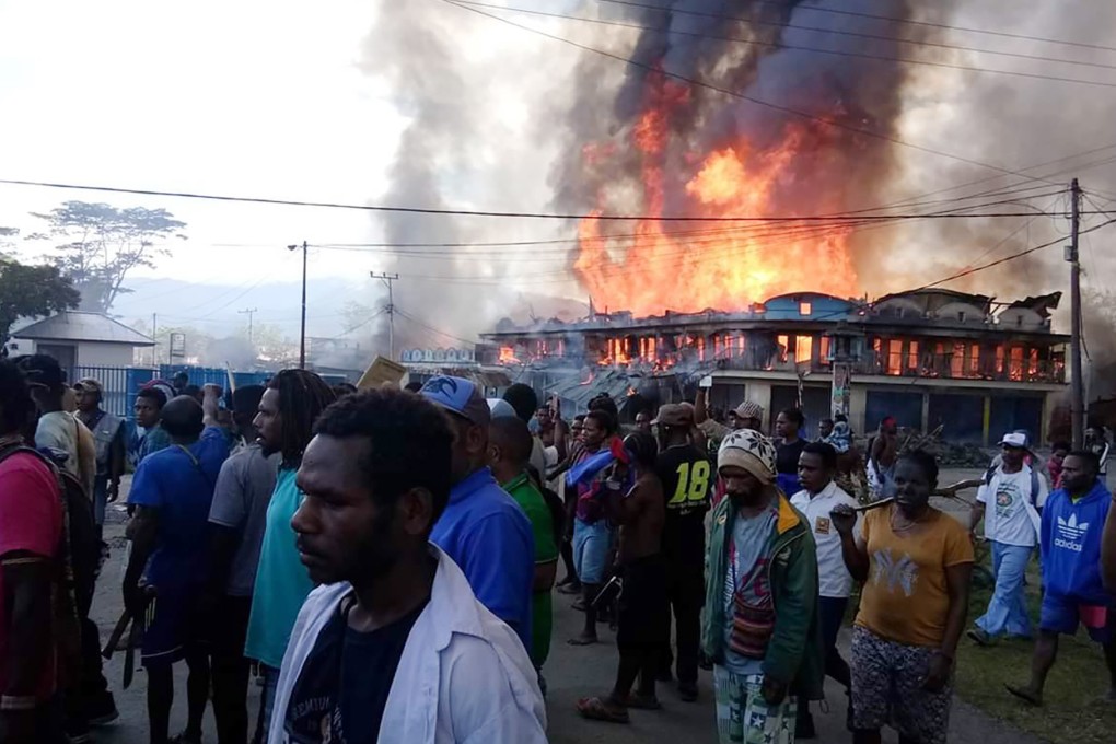 People gather as shops burn in the background during a protest in Wamena in Papua. Photo: AP