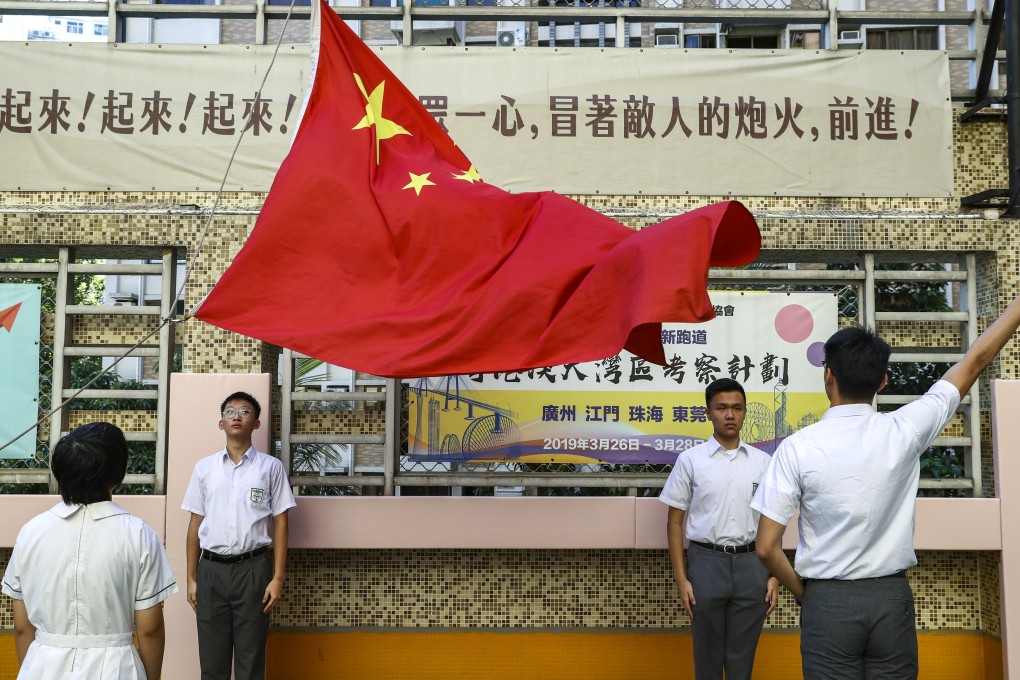 Students from Pui Kiu Middle School in North Point observe a national flag-raising ceremony on campus. Photo: Nora Tam