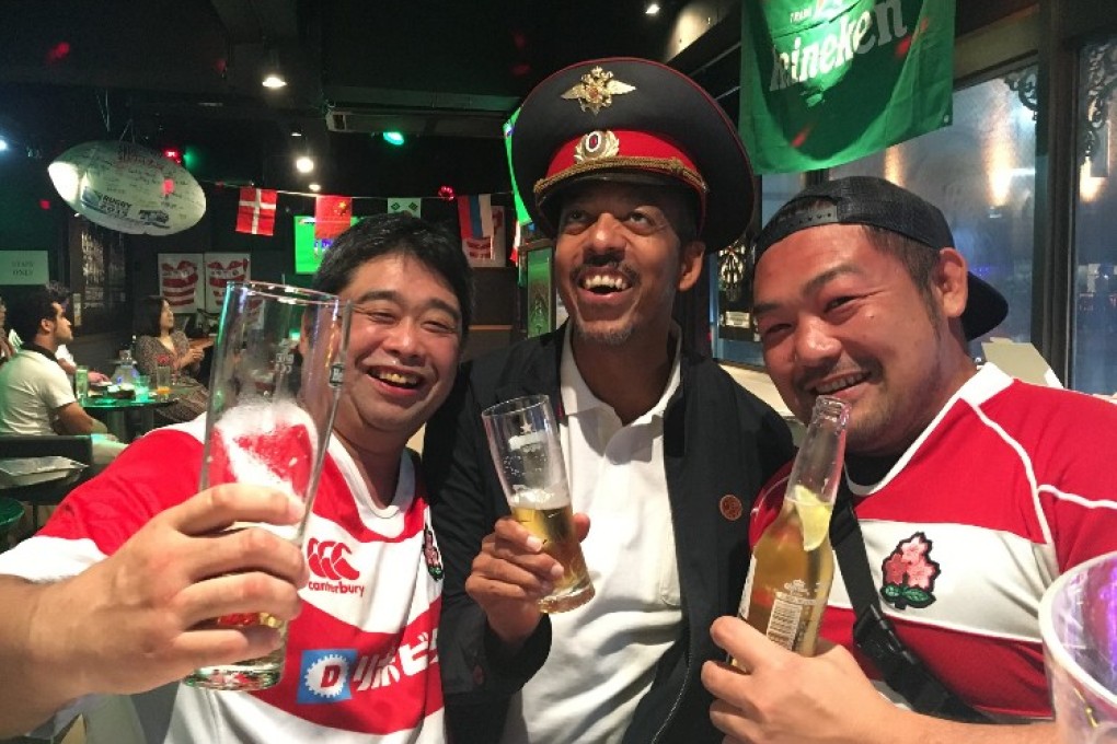 Luis Matos, center, welcomes a few rugby revellers to his downtown pub.