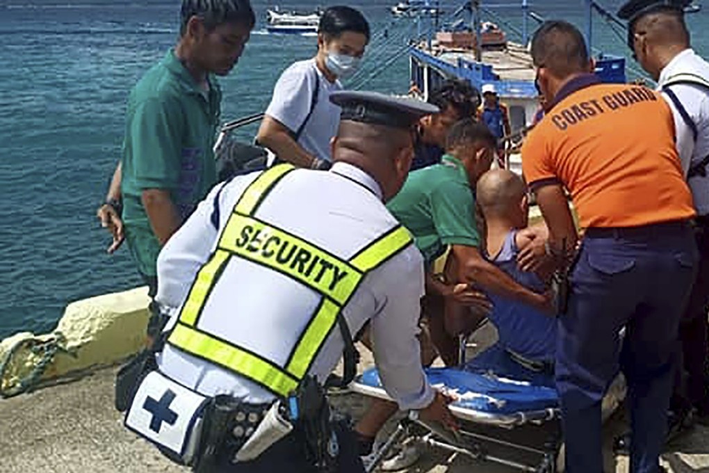 Coast guard personnel move a survivor to an ambulance. Photo: Philippine Coast Guard Via AP