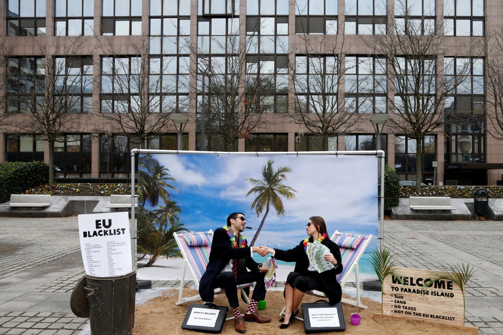 Activists stage a protest against the backdrop of a mock tropical island beach representing a tax haven, outside a meeting of European Union finance ministers in Brussels, Belgium, in December 2017. Improved corporate disclosures include recognising the sustainability impacts and relevance of issues such as tax payments. Photo: Reuters